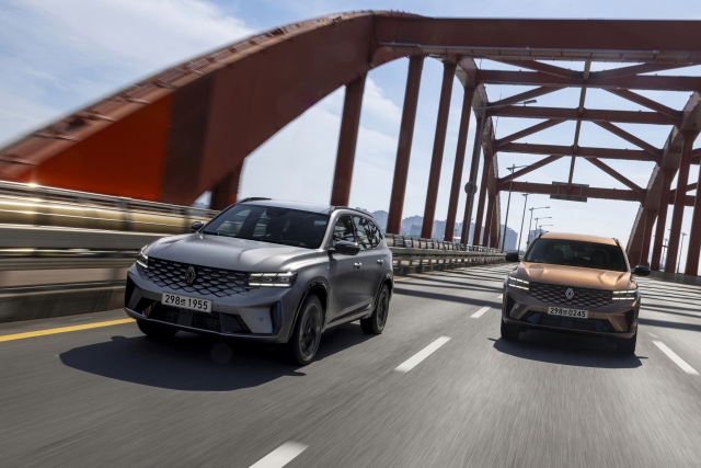 The new Renault Grand Koleos hybrid sport utility vehicles, shown in Urban Grey (left) and Mineral Copper (right), cruise across a bridge in South Korea. (Renault Korea)