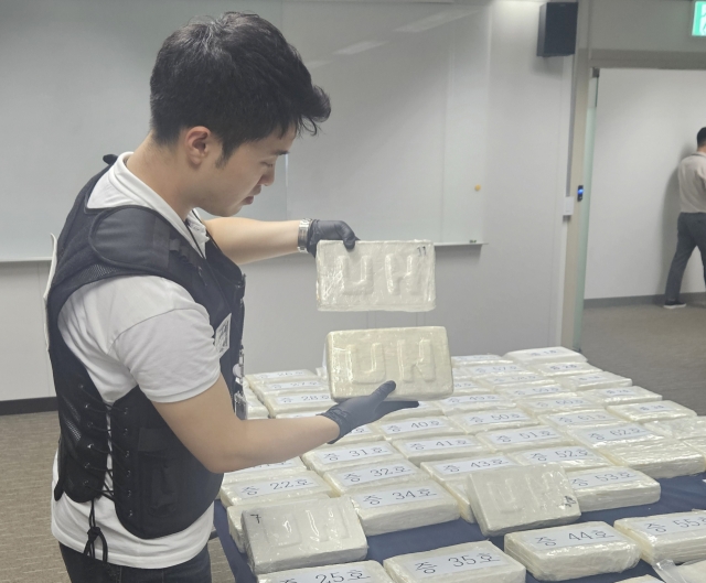 An official holds up cocaine that was seized while being smuggled into South Korea, in an Aug. 19 briefing held at the headquarters of the Korea Coast Guard Region-Central in Incheon. (Yonhap)