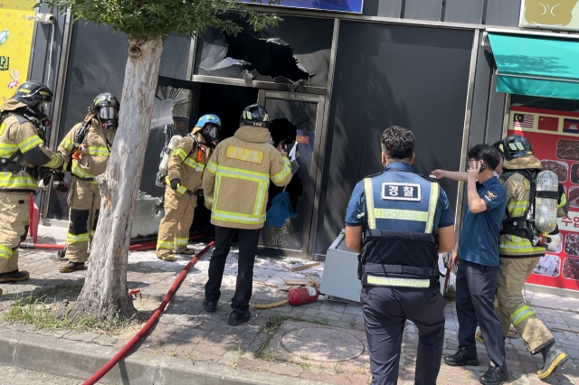 This photo provided by the Jeonnam Fire Service shows firefighters and police officers investigating the scene of an arson at a commercial building in Yeongam-gun, South Jeolla Province, Sunday. (Jeonnam Fire Service)