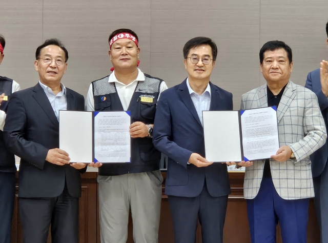 Gyeonggi Province Gov. Kim Dong-yeon (2nd from R) poses with representatives of unionized bus drivers and bus company owners in Suwon, south of Seoul, on Wednesday, after reaching a last-minute wage hike deal to avert a general strike. (Yonhap)