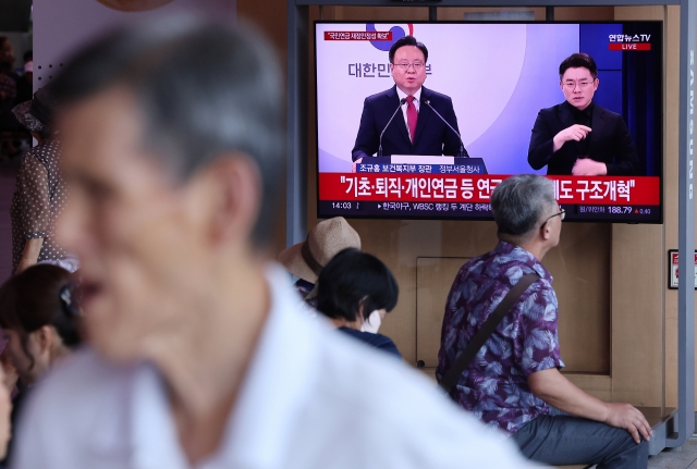 A pedestrian walk past a TV screen broadcasting Welfare Minister Cho Kyoo-hong's press briefing in Seoul on Wednesday. (Yonhap)