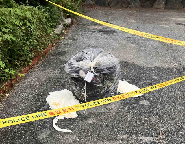 A police line is set up around a trash-carrying balloon presumed to be sent by North Korea in Chuncheon, Gangwon Province on Sunday. (Yonhap)