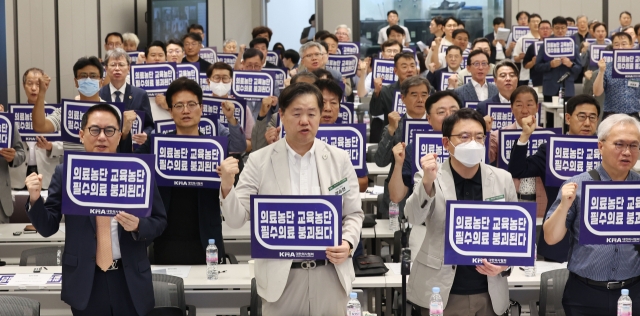 Participants of an emergency meeting of the Korean Medical Association hold signs in Seoul in protest of the government's plan to drastically increase the medial school admissions quota, on Aug. 31. (Yonhap)