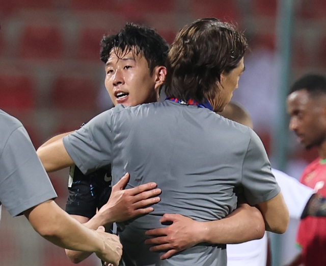 Hong Myung-bo (right) embraces Son Heung-min after South Korea won 3-1 over Oman in the World Cup qualification match at the Sultan Qaboos Sports Complex in Muscat on Tuesday. (Yonhap)