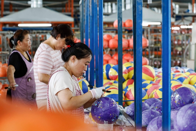 This photo taken on Saturday shows employees producing basketballs at a factory in Sihong, in eastern China's Jiangsu province. (AFP-Yonhap)