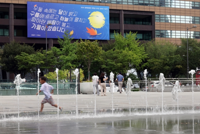 A child runs through a fountain on Gwanghwamun Square in Seoul on Wednesday, amid an unrelenting heat wave across the nation. (Yonhap)