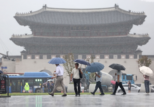 Pedestrians walk past Gwanghwamun Square with umbrellas in the middle of a rain shower on Sept. 5. (Yonhap)