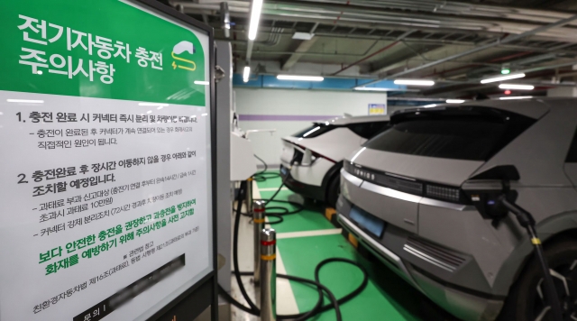 Precautionary signage instructing drivers to disconnect the charger and move their vehicle immediately after charging to prevent fires at an electric vehicle charging station in a Seoul underground parking lot. (Newsis)