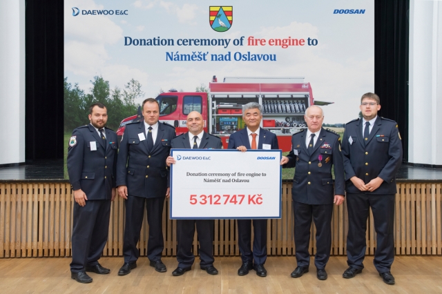 Daewoo E&C Chairman Jung Won-ju (center right), along with Martin Krupa (fourth from right), commander of Namest nad Oslavou's fire protection unit, and other firefighters, pose for a photo during the ceremony in Namest nad Oslavou, Trebic District, Czech Republic, on Thursday. (Daewoo E&C)