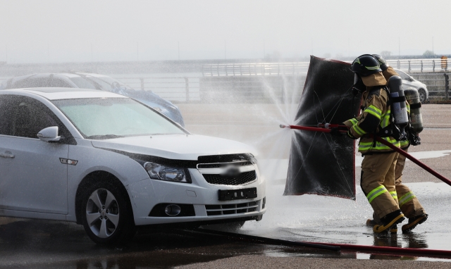 Firefighters demonstrate how to extinguish a fire on an electric vehicle in Pyeongtaek, Gyeonggi Province, Friday. (Yonhap)