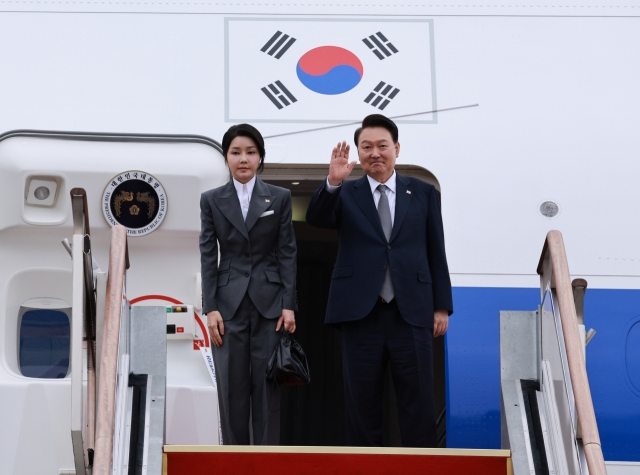 First Lady Kim Keon Hee (left) and President Yoon Suk Yeol wave from Air Force One as the couple departs for the Philippines on Sunday. (Yonhap)