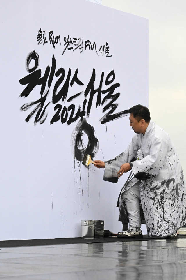 Artist Lee Sang-hyun creates calligraphy during the opening event of Wellness Seoul 2024 on Sunday. (Im Se-jun/The Korea Herald)