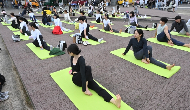 Participants join in an outdoor yoga session with activewear brand Mulawear on the south end of Banpo Bridge during Wellness Seoul 2024 on Sunday. (Im Se-jun/The Korea Herald)