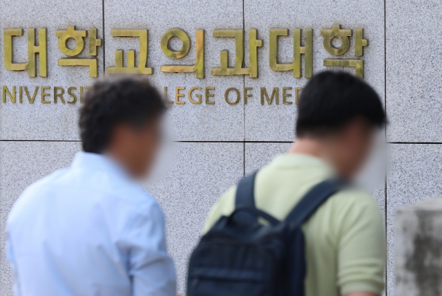 Pedestrains pass by a medical school in Seoul (Yonhap)