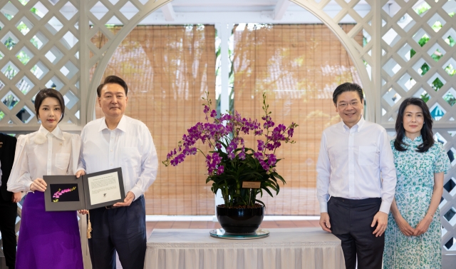 South Korean first lady Kim Keon Hee (from left), President Yoon Suk Yeol, Singapore's Prime Minister Lawrence Wong and Wong's wife Loo Tze Lui pose for a photo as they attended the orchid naming ceremony at Singapore Botanic Gardens Tuesday. (Pool photo via Yonhap)