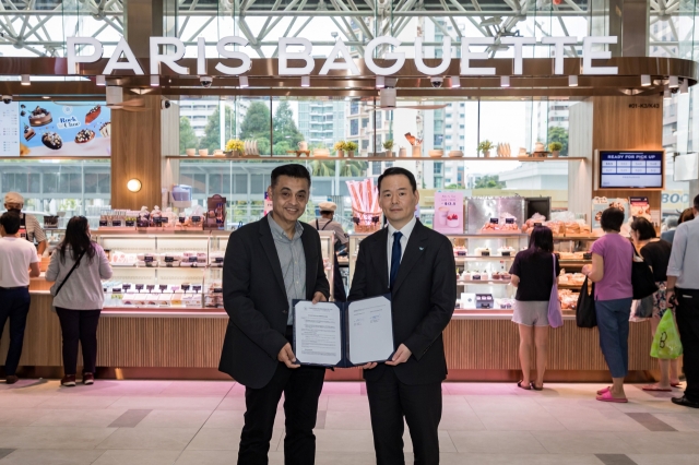 SPC Group CEO Hur Jin-soo (right) and Berjaya Food CEO Sydney Lawrance Quays sign a master franchising agreement at a Paris Baguette store in Parkway Parade, Singapore, on Monday. (SPC Group)