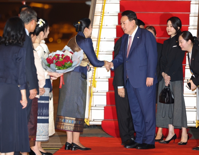 President Yoon Suk Yeol (center) receives a bouquet upon arrival at Wattay International Airport in Vientiane, Laos, on Wednesday. (Yonhap)