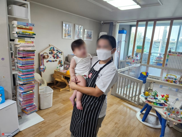 A Filipino caregiver holds an infant at a home in Seoul. (The Seoul Metropolitan Government)