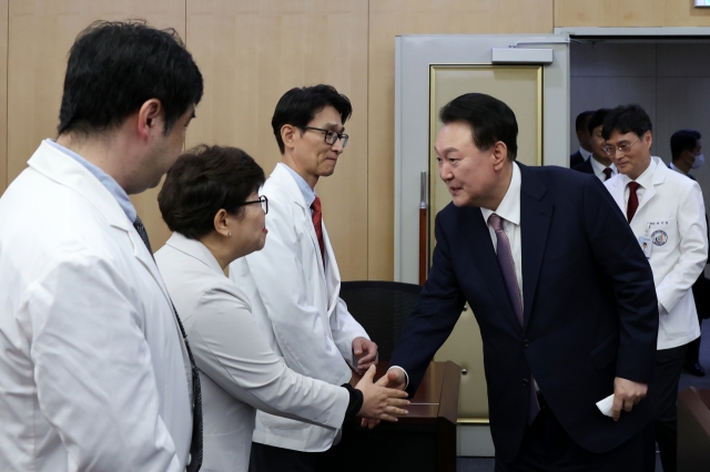 President Yoon Suk Yeol (fourth from left) is greeted by medical staff at Jeju National University Hospital on Tuesday. (Presidential office)