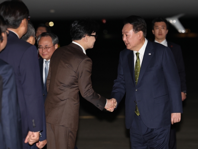 President Yoon Suk Yeol (right) shakes hands with Han Dong-hoon, leader of the ruling People Power Party, at Seoul Air Base in Seongnam, south of Seoul, in this file photo taken Oct. 11, upon Yoon's return from his three-nation Southeast Asia trip. (Yonhap)