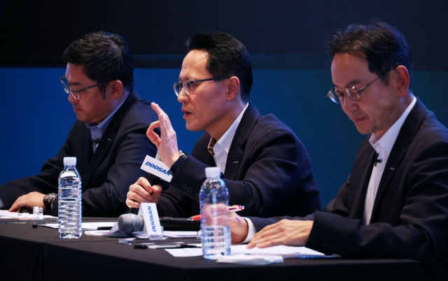 From left: Ryu Jung-hoon, CEO of Doosan Robotics, Park Sang-hyun, CEO of Doosan Enerbility, and Scott Park, CEO of Doosan Bobcat, answer questions during a press conference held at the Plaza Hotel in Seoul on Monday. (Doosan Group)