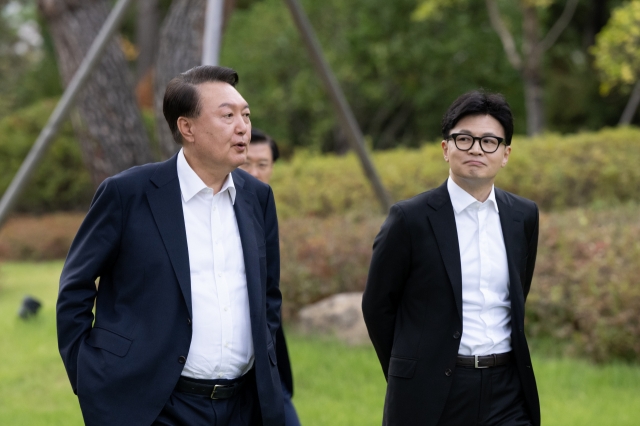 President Yoon Suk Yeol (left) speaks to People Power Party Chair Han Dong-hoon while walking to the presidential office for their meeting in Yongsan, central Seoul, Monday afternoon. (Presidential office)