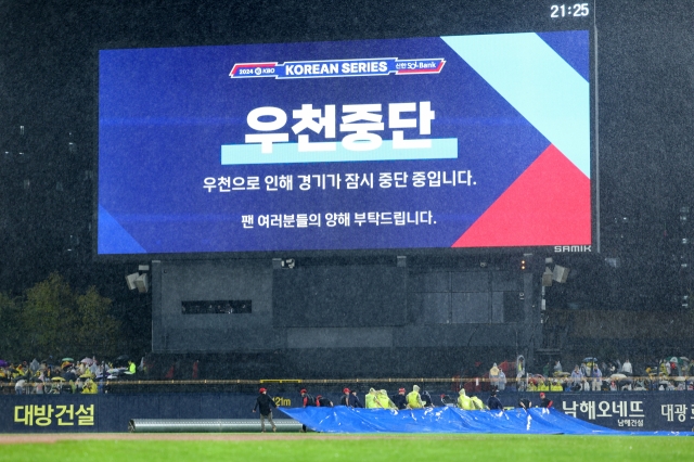 Groundskeepers bring out the tarp at Gwangju-Kia Champions Field in Gwangju, 270 kilometers south of Seoul, with Game 1 of the Korean Series between the Kia Tigers and the Samsung Lions in rain delay on Monday. (Yonhap)