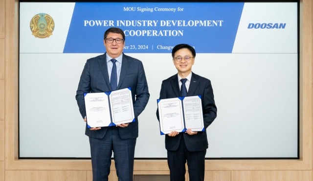 Doosan Enerbility’s head of marketing Jungkwan Kim (right) poses for a photo with Kazakhstan's Minister of Energy Almassadam Satkaliyev at an MOU signing ceremony held at the firm’s headquarters in Changwon on Wednesday. (Doosan Enerbility)