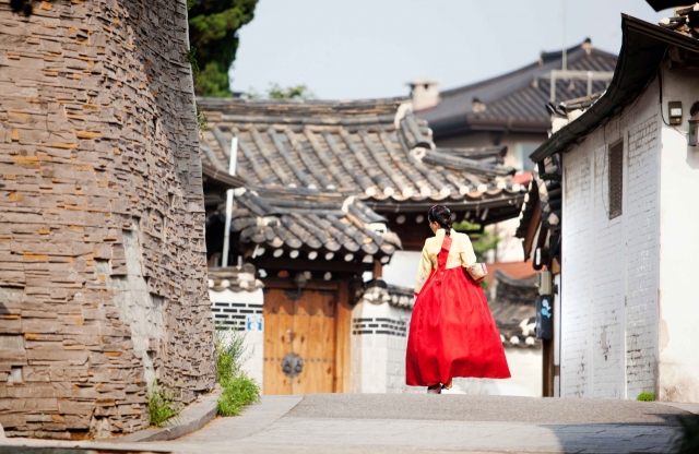 A traveler dressed in hanbok walks along a street in Bukchon Hanok Village in Jongno-gu, central Seoul. (Korea Tourism Organization)