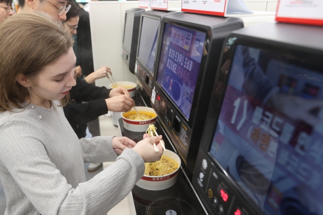 Foreign visitors try Korea’s instant noodle ramyeon at CU Hongdae on Friday. (Yonhap)