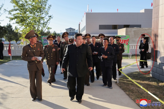 n this photo provided by North Korea’s official Korean Central News Agency, Kim Yo-jong (circled in red), the sister of North Korean leader Kim Jong-un, watches as Kim Jong-un (front, in a black jacket) visits a construction site in North Pyeongan Province on Oct. 6. (Yonhap)