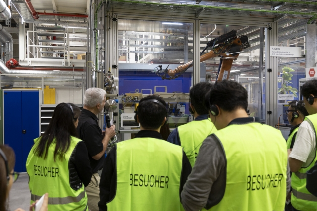 Korean reporters witness a Mercedes-Benz technician demonstrating the helium leak test chamber, where robotic arms detect microscopic leaks in EV battery packs to ensure airtight sealing and safety. (Mercedes-Benz)