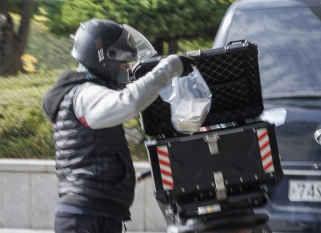 A delivery worker parks his motorcycle in a parking lot in Seoul. (Yonhap)