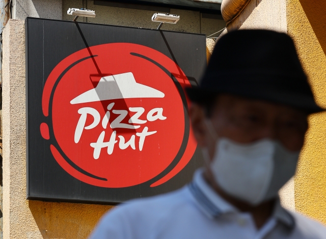 A man passes by a Pizza Hut store in Seoul. (Newsis)