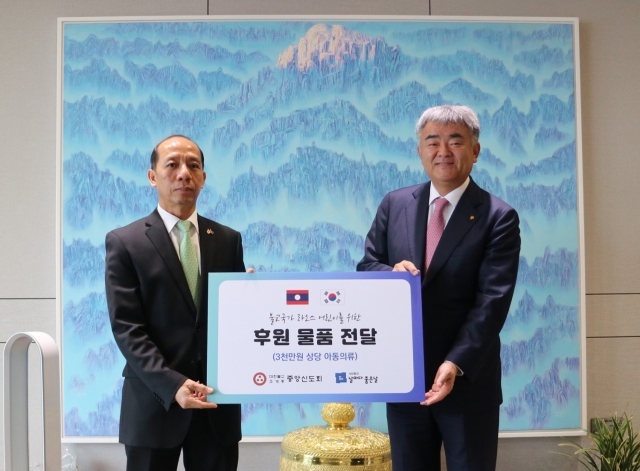 Jung Won-ju (right), chairman of Herald Media Group and Daewoo E&C, and Alounkone Boulommavong, deputy chief of mission of the Laotian Embassy in South Korea, pose for a photo at a donation ceremony in Seoul on Thursday. (Lay Buddhist Association of the Jogye Order of Korean Buddhism)