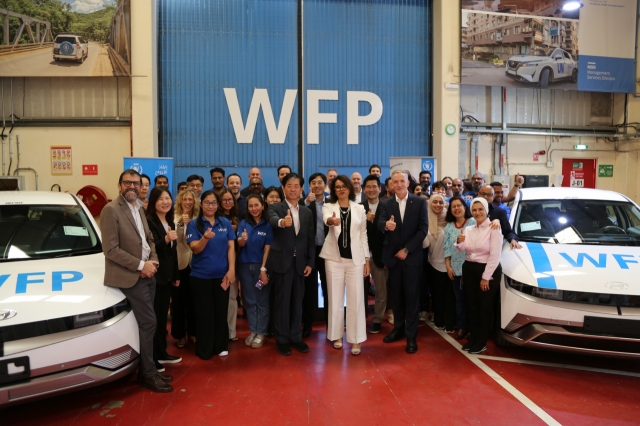 Sara Adam (center), UN World Food Programme director of management services; Lee Hang-soo (center left), Hyundai’s senior vice president of policy support; and Stephen Anderson (center right), director of WFP’s UAE office, pose with WFP staff alongside the donated Ioniq 5 vehicles at a handover ceremony in Dubai on Thursday. (Hyundai Motor Group)