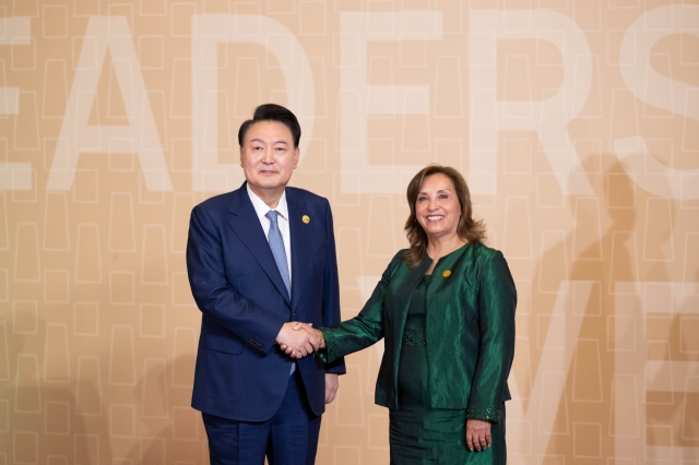 President Yoon Suk Yeol (left) shakes hands with his Peruvian counterpart, Dina Boluarte, ahead of a session of the Asia-Pacific Economic Cooperation summit on Saturday. (Yonhap)