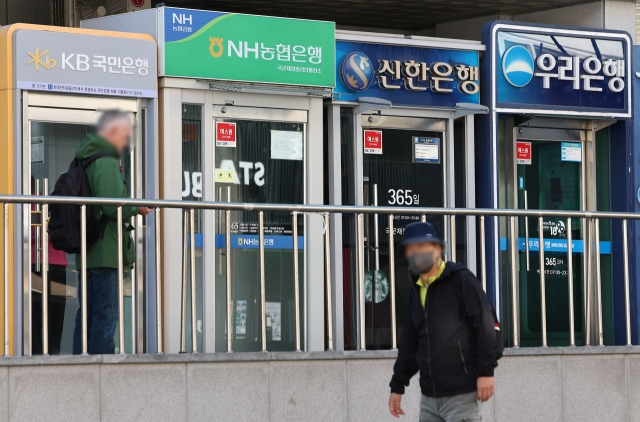 People pass by ATMs of major banks in Seoul, Oct. 20. (Yonhap)