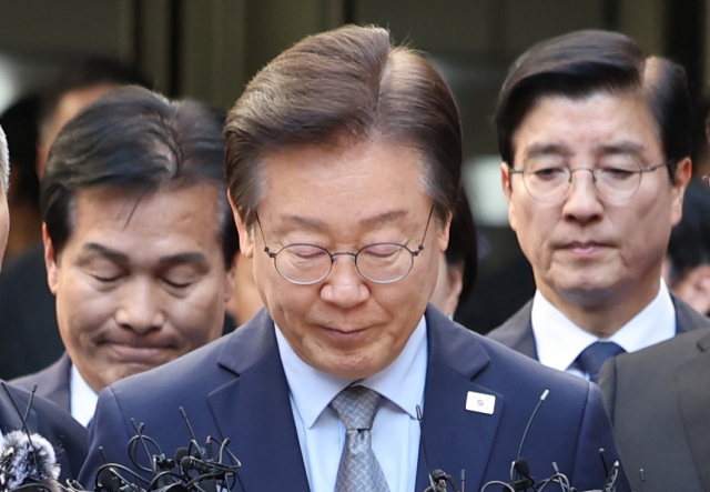 Lee Jae-myung (center), the leader of the main opposition Democratic Party, responds to reporters' questions after receiving a suspended one-year prison sentence for election law violations, at the Seoul Central District Court on Friday. (Yonhap)