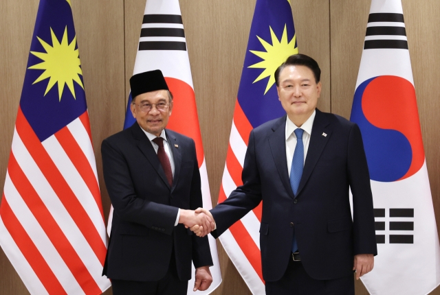 President Yoon Suk Yeol (right) and Malaysia's Prime Minister Anwar Ibrahim shake hands as they met for a summit at the presidential office in Seoul on Monday. (Yonhap)