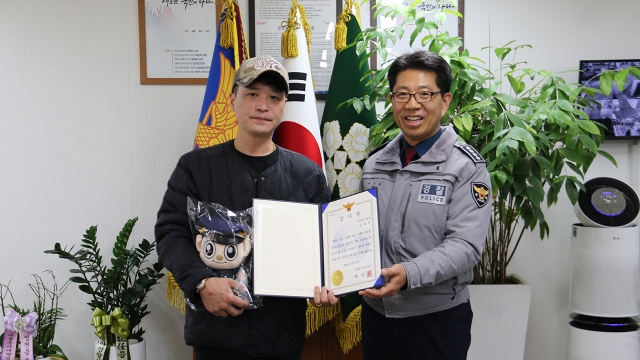 A Seongdong Police Station official (right) gives the acclimation award to the citizen who rescued a student jumping off the bridge. (Seoul Seongdong Police Station)