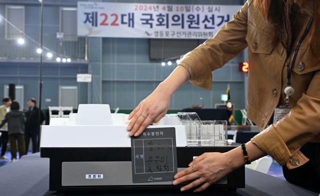 An official of the National Election Committee checks a voting equipment prior to the parliamentary elections in this April 9 file photo taken in Seoul. (Lee Sang-seob/The Korea Herald)