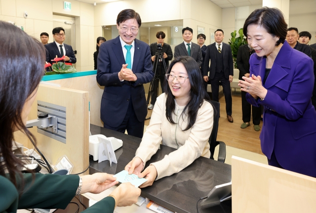 The 10,000th holder of Hana Bank's special savings account for small and medium-sized firms receives her bankbook at a Seoul branch earlier this month, with Hana Bank CEO Lee Seung-lyul (left) and Minister of SMEs and Startups Oh Young-ju in attendance. (Hana Bank)