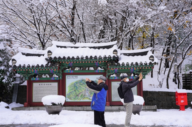 Visitors capture winter moments with smartphones near Gwanaksan's entrance on Thursday. (Lee Si-jin/The Korea Herald)