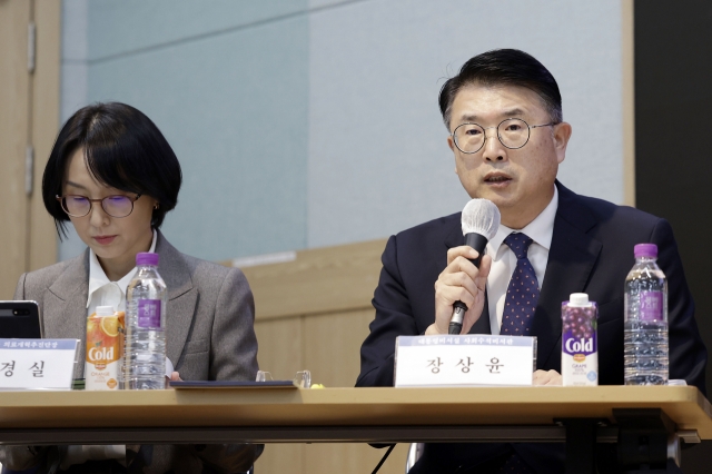 Jang Sang-yoon (right), a senior presidential secretary for social policy, listens to a question by a trainee doctor during a debate session on the medical reform at Seoul National University College of Medicine in Seoul on Oct. 10. (Newsis)