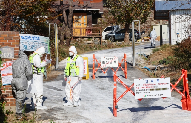 In this file photo, quarantine officials control entry into a poultry farm in Ganghwa County in Incheon on Nov. 18, following an outbreak of highly pathogenic avian influenza. (Yonhap)