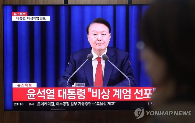 A person watches the TV screen as President Yoon Suk Yeol declares emergency martial law in a televised national address on Tuesday evening. (Yonhap)