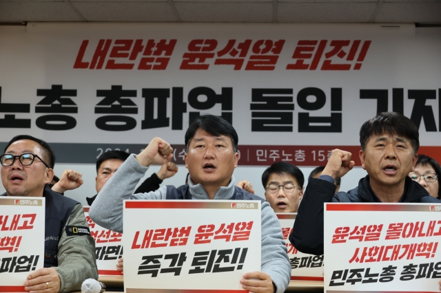 At a press conference on Wednesday in Jung-gu, Seoul, members of the Korean Confederation of Trade Unions hold placards declaring, “Impeach Yoon Suk Yeol, the man behind the coup!” The umbrella union formally announced its decision to launch an indefinite general strike, calling for the president’s resignation. (Yonhap)