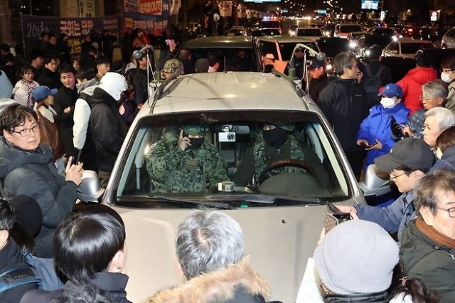 A photo shows people blocking a car carrying military personnel from entering the National Assembly. (X user @woochick2)