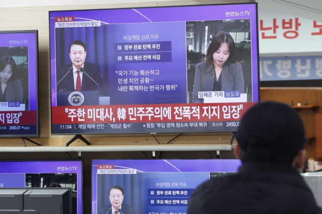 A citizen watches reports regarding the declaration and subsequent lifting of martial law at an electronics store in Yongsan-gu, Seoul. (Yonhap)